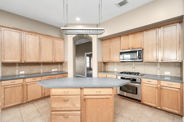 kitchen with decorative backsplash, appliances with stainless steel finishes, and a kitchen island