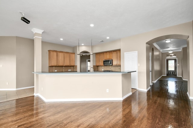 kitchen featuring decorative backsplash, dark wood-type flooring, a spacious island, and sink