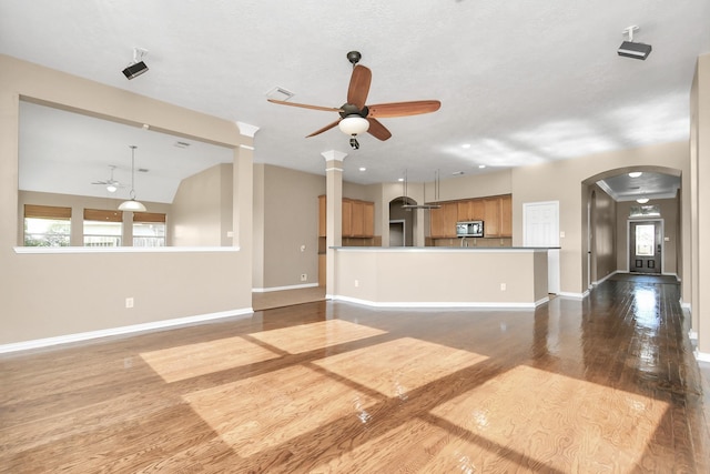 unfurnished living room with hardwood / wood-style flooring, ceiling fan, a wealth of natural light, and vaulted ceiling