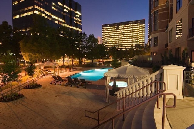 pool at dusk featuring a gazebo and a patio area