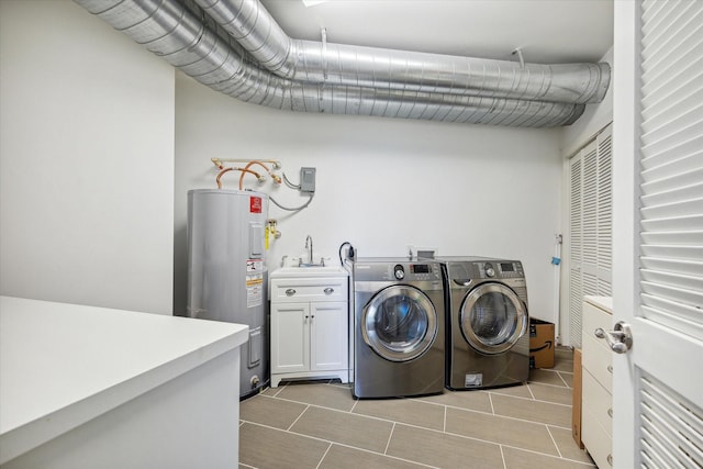 washroom with cabinets, electric water heater, sink, and washing machine and dryer