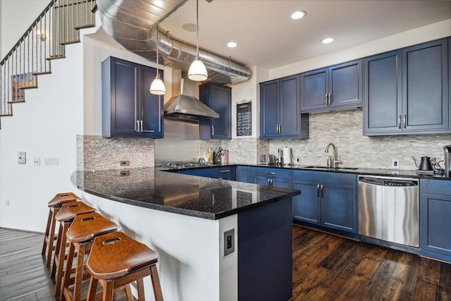 kitchen with kitchen peninsula, appliances with stainless steel finishes, sink, blue cabinetry, and hanging light fixtures