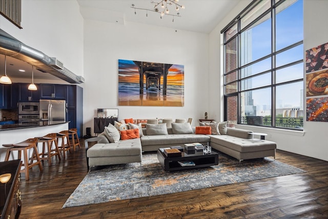 living room with a high ceiling, dark hardwood / wood-style floors, and an inviting chandelier