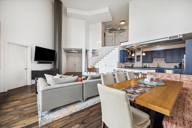 dining area with sink, a towering ceiling, and dark wood-type flooring