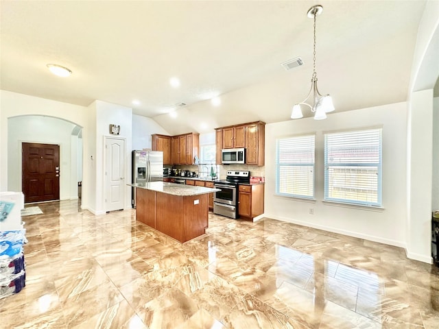 kitchen featuring a center island, hanging light fixtures, vaulted ceiling, stainless steel appliances, and a chandelier