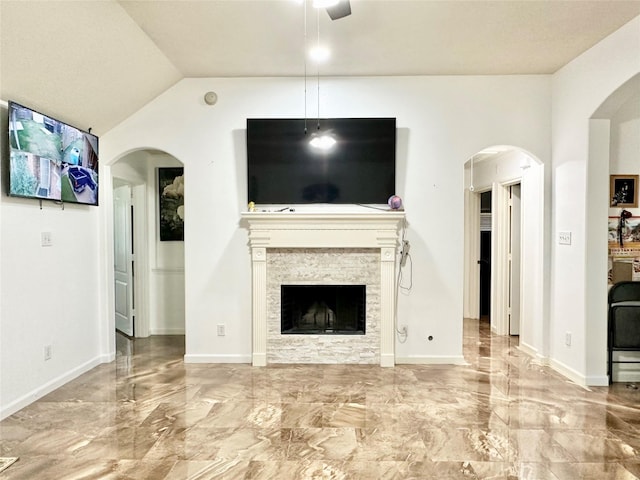 unfurnished living room featuring a stone fireplace and ceiling fan