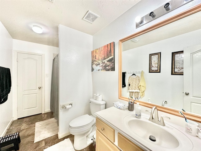 bathroom with vanity, a textured ceiling, and toilet