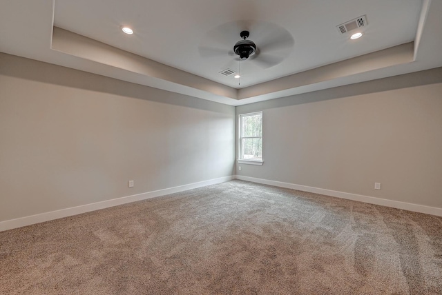 carpeted empty room with a tray ceiling and ceiling fan