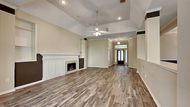 unfurnished living room featuring light wood-type flooring, vaulted ceiling, built in features, and ceiling fan