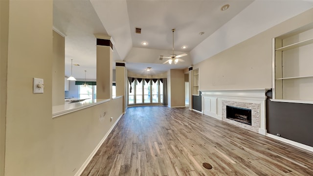 unfurnished living room featuring a stone fireplace, ceiling fan, light hardwood / wood-style floors, and lofted ceiling