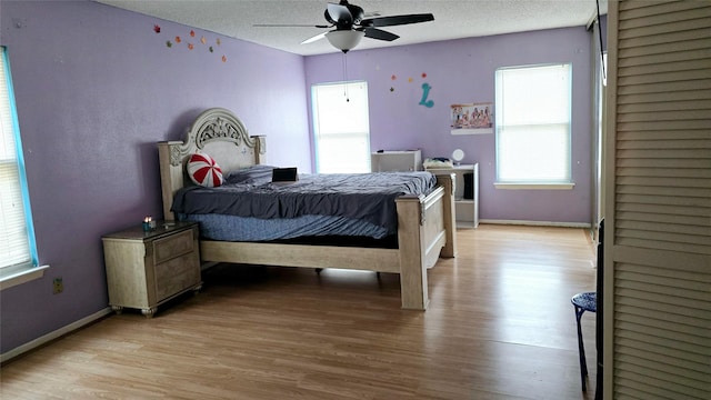 bedroom featuring ceiling fan, light hardwood / wood-style floors, and a textured ceiling