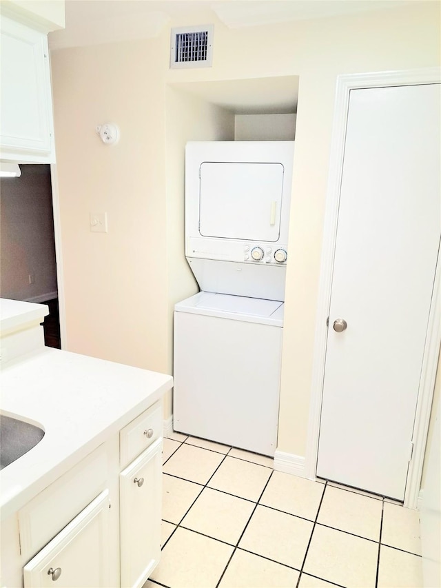 laundry room with stacked washer and dryer and light tile patterned floors