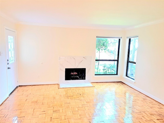 unfurnished living room featuring a wealth of natural light, crown molding, and a high end fireplace