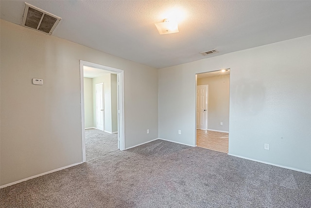 empty room featuring a textured ceiling and light carpet