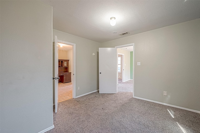 empty room with light carpet and a textured ceiling