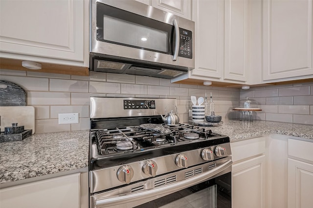 kitchen with tasteful backsplash, white cabinetry, and stainless steel appliances