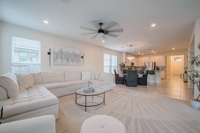 tiled living room featuring ceiling fan with notable chandelier and a wealth of natural light