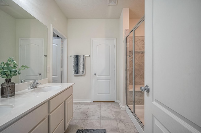 bathroom featuring a textured ceiling, vanity, and an enclosed shower