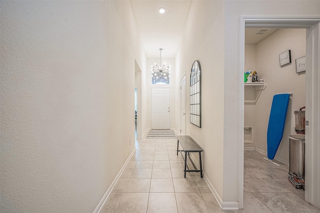 hall with light tile patterned flooring and an inviting chandelier