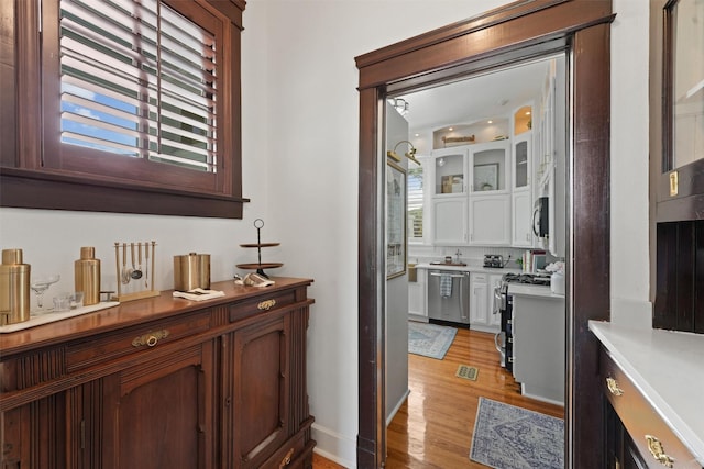 bar with white cabinetry, appliances with stainless steel finishes, and light hardwood / wood-style flooring