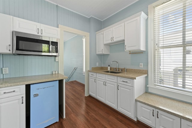 kitchen with dark hardwood / wood-style flooring, white dishwasher, crown molding, sink, and white cabinets