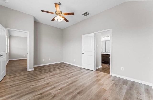 unfurnished bedroom featuring ensuite bath, ceiling fan, light hardwood / wood-style flooring, and lofted ceiling