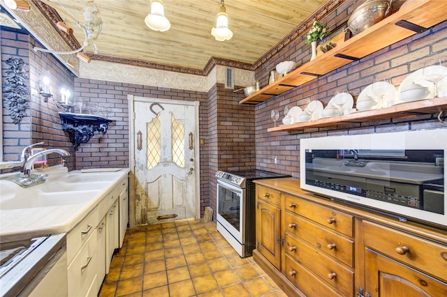 kitchen with electric stove, hanging light fixtures, sink, wood ceiling, and brick wall