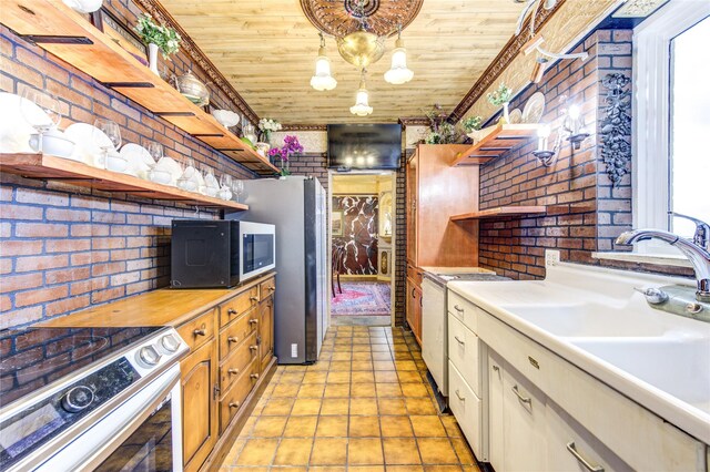 kitchen featuring brick wall, wood ceiling, white range with electric stovetop, white cabinetry, and hanging light fixtures