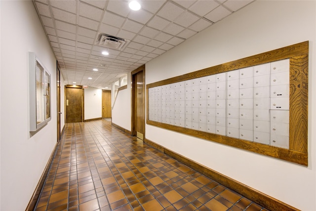 hall featuring a paneled ceiling and a mail area