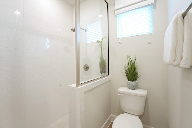 bathroom with a tile shower and toilet