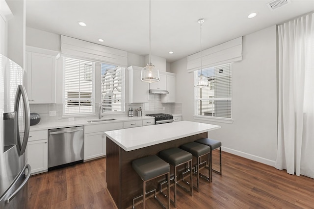 kitchen featuring decorative light fixtures, stainless steel appliances, white cabinetry, and sink