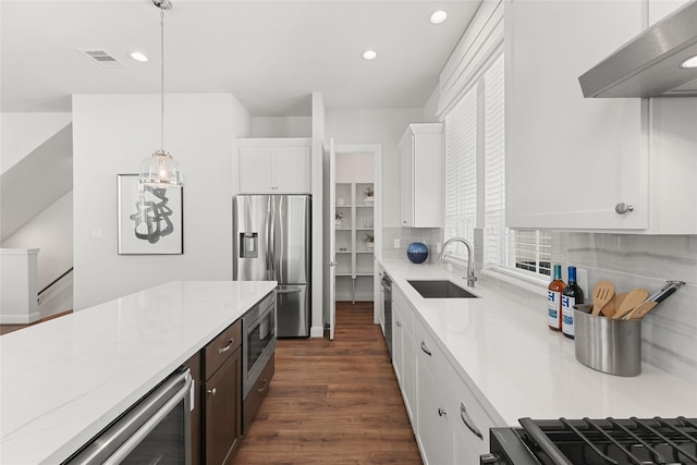 kitchen featuring stainless steel appliances, extractor fan, sink, pendant lighting, and white cabinets