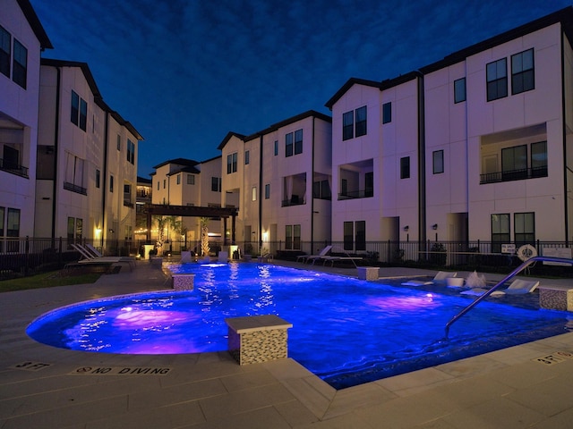 pool at night featuring pool water feature