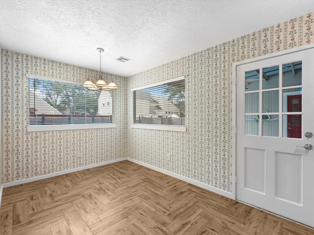 unfurnished dining area with a textured ceiling, parquet floors, and a chandelier