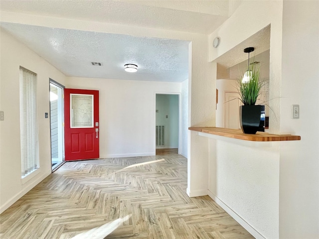 foyer featuring light parquet flooring and a textured ceiling