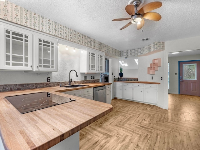 kitchen featuring dishwasher, white cabinetry, sink, kitchen peninsula, and black stovetop