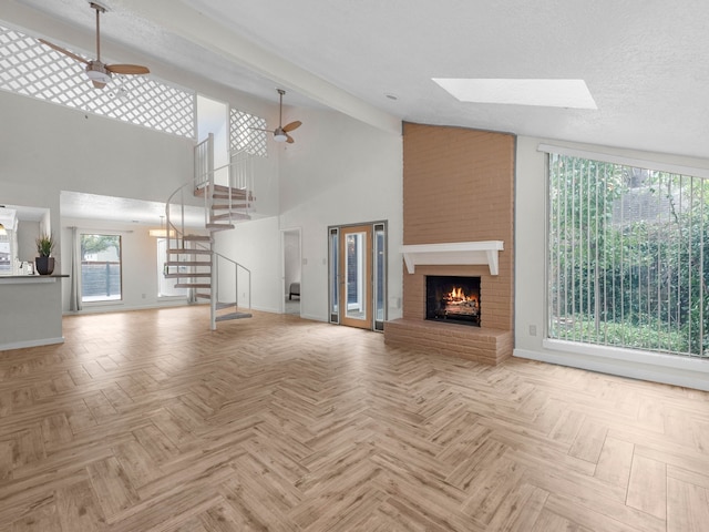 unfurnished living room with ceiling fan, a skylight, and light parquet floors