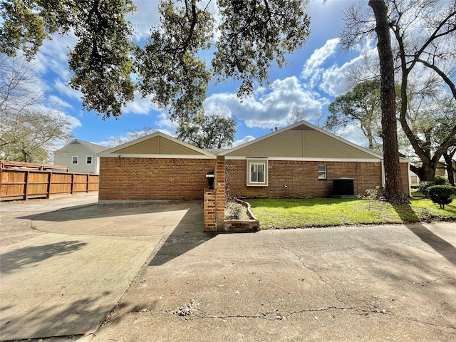 back of property featuring brick siding, a lawn, fence, and central air condition unit