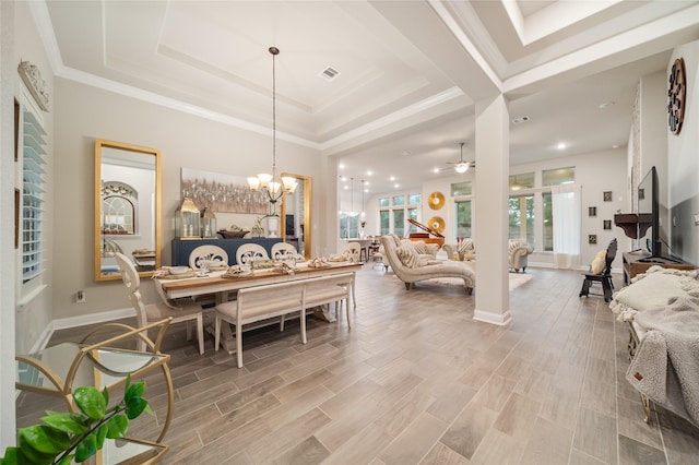 dining space with wood-type flooring, ceiling fan with notable chandelier, a raised ceiling, and crown molding