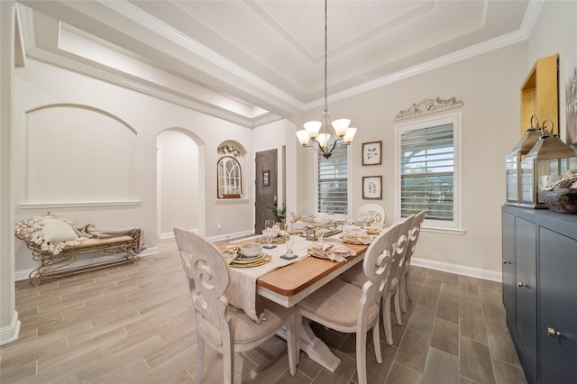 dining area with a chandelier, hardwood / wood-style floors, a raised ceiling, and crown molding