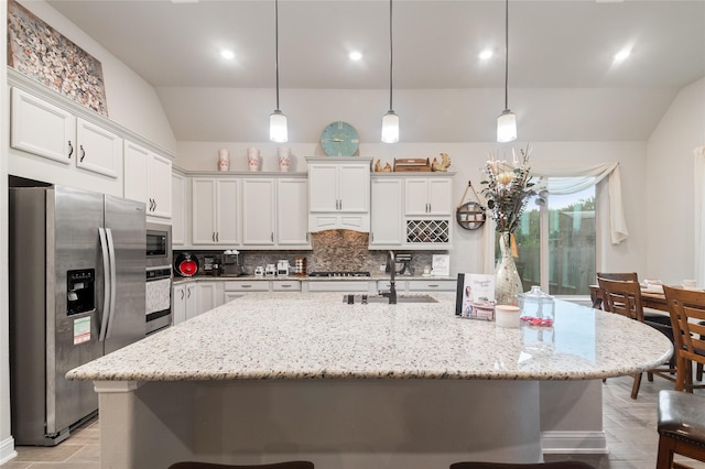 kitchen with sink, tasteful backsplash, vaulted ceiling, a kitchen island with sink, and appliances with stainless steel finishes