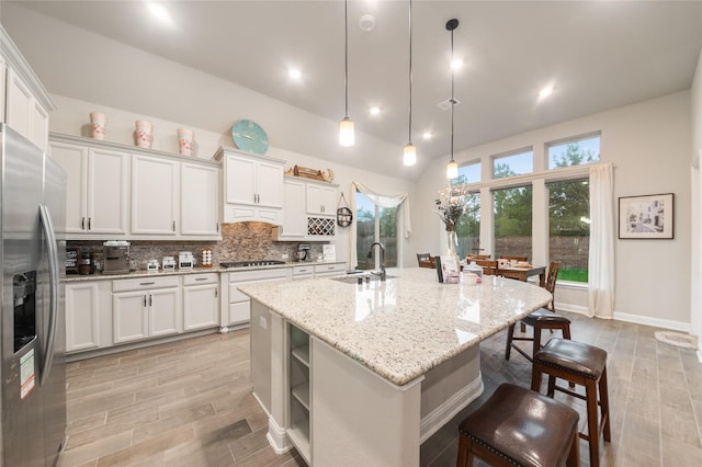 kitchen with white cabinetry, sink, hanging light fixtures, an island with sink, and appliances with stainless steel finishes