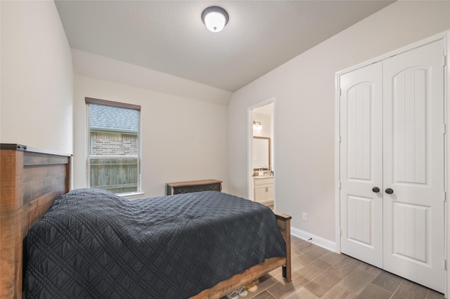 bedroom with vaulted ceiling, connected bathroom, and a closet