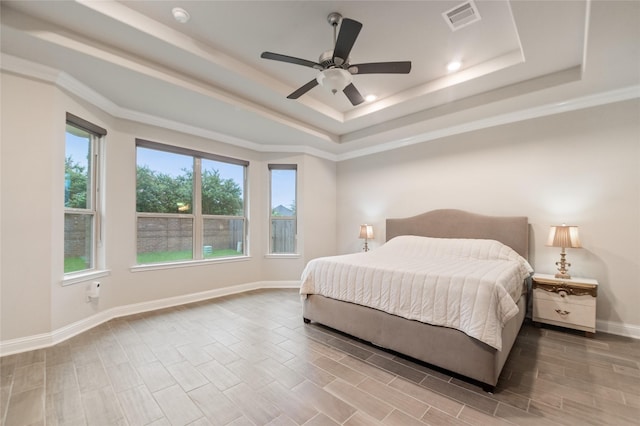 bedroom with a tray ceiling, multiple windows, and ceiling fan