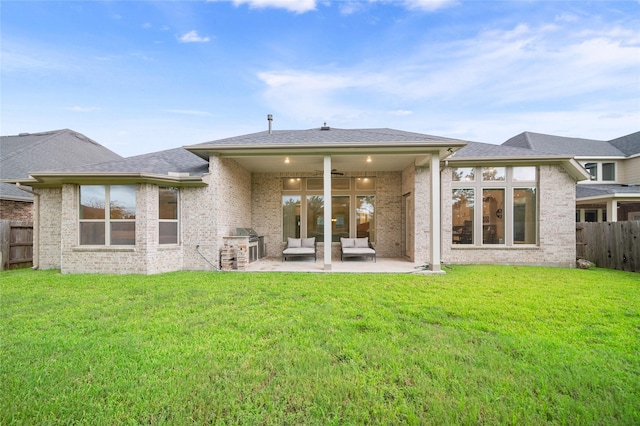 rear view of property with a patio, ceiling fan, exterior kitchen, and a lawn