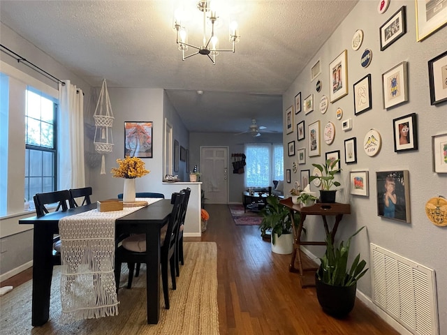 dining space with ceiling fan with notable chandelier, wood-type flooring, and a textured ceiling