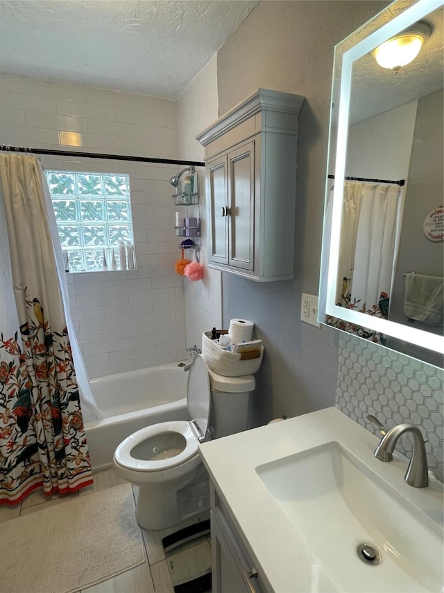 full bathroom featuring tile patterned floors, shower / bath combination with curtain, a textured ceiling, toilet, and vanity