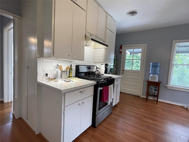 kitchen with gas stove, white cabinetry, backsplash, and a wealth of natural light