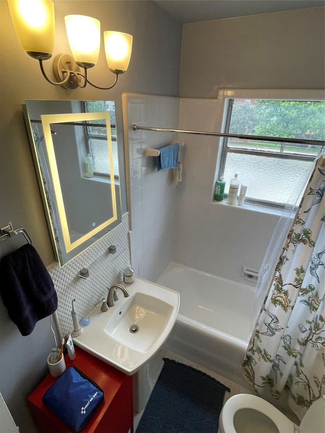 full bathroom featuring sink, tasteful backsplash, a notable chandelier, toilet, and shower / tub combo with curtain