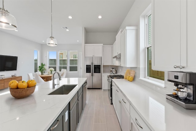 kitchen with appliances with stainless steel finishes, decorative light fixtures, white cabinetry, and sink